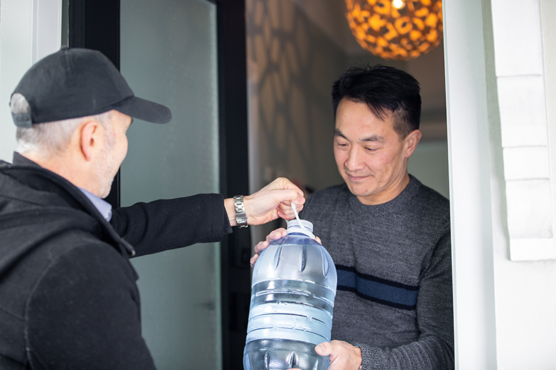 A man giving his neighbour a large bottle of water
